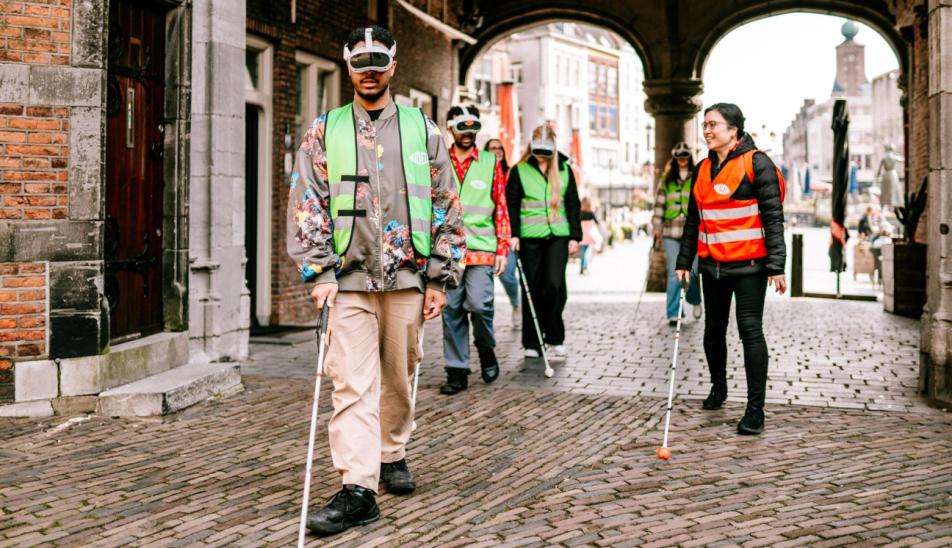 Visitors during the *Expedition Ribbelroute: through the city centre of Nijmegen*, with guide Melly, walking under an archway toward the Sint Stevenskerk in Nijmegen.