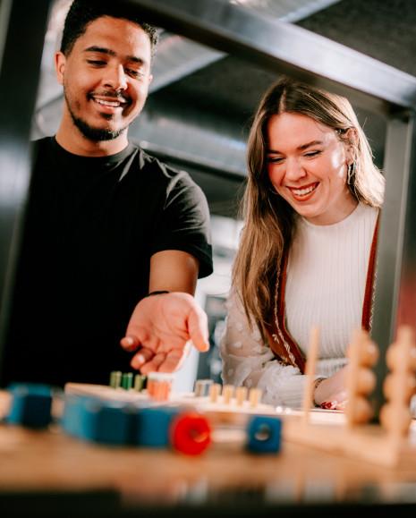 Two visitors are playing Ludo on the do-square.