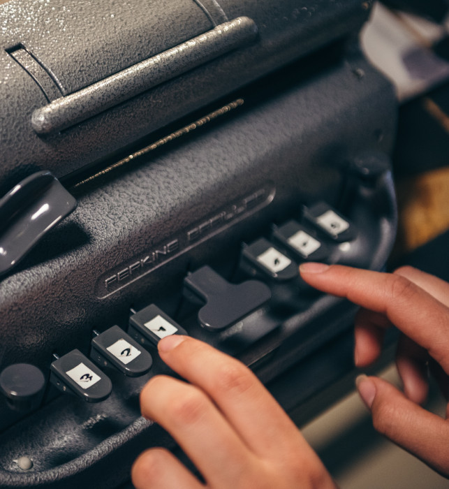 A braille typewriter, with a visitor attempting to type in braille.